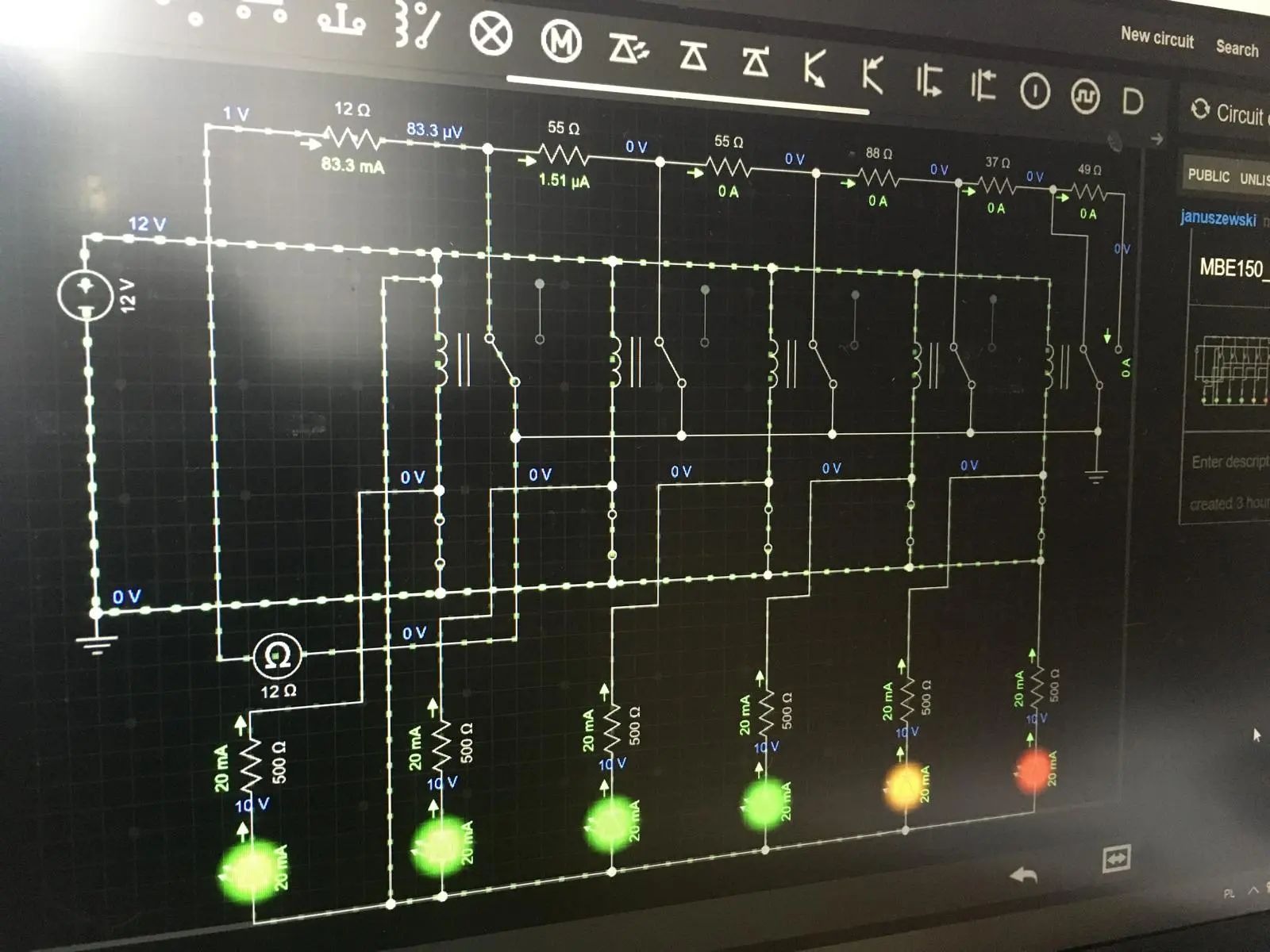 Schemat elektryczny z symulacji komputerowej, przedstawiający obwód z przekaźnikami, rezystorami i diodami LED o różnych kolorach, wyświetlany na ekranie monitora z siatką w tle.