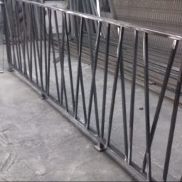 Dav-bud - Surowa, spawana konstrukcja metalowa z ukośnymi prętami w warsztacie, widoczne ślady spawania i niedoskonałości wykończenia.