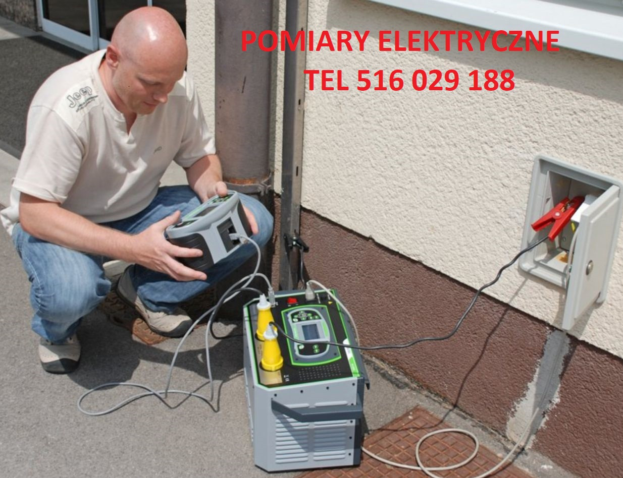 Elektryk w trakcie pracy, używa specjalistycznego sprzętu pomiarowego do sprawdzenia instalacji w puszce na elewacji budynku. Widoczne kable i zaciski podłączone do urządzenia.