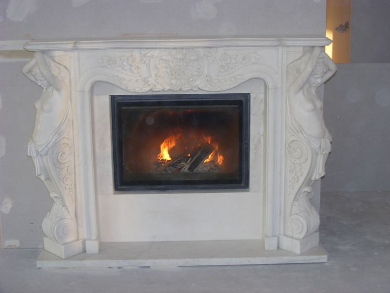 Marmurowy portal kominkowy z płaskorzeźbami kobiecych postaci podtrzymujących górną część, wkład kominkowy z paleniskiem, ściana i podłoga w stanie surowym.