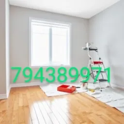 Pokój po malowaniu ścian na jasny odcień, widoczna drabina malarska z puszką farby, kuweta z wałkiem oraz zabezpieczona folią podłoga z parkietu.