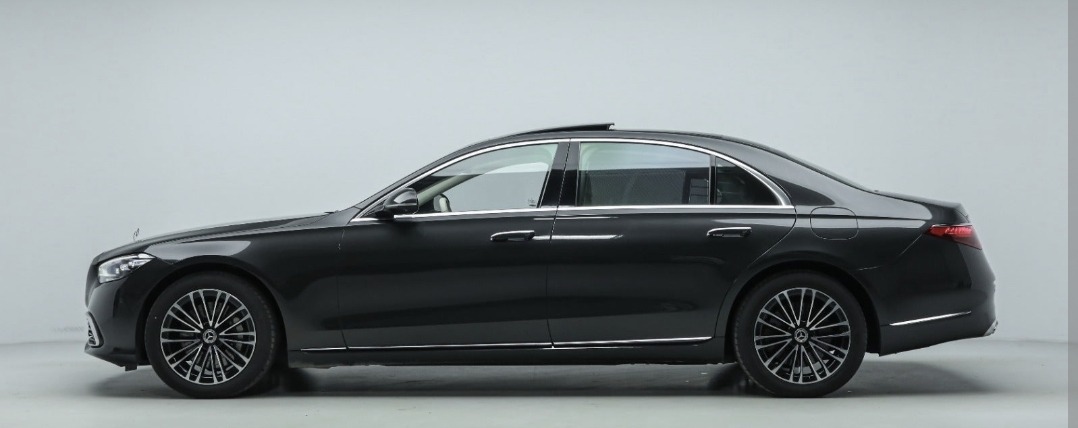Elegancki, ciemnoszary Mercedes-Benz klasy S z panoramicznym dachem, widoczny z profilu na jasnym tle studyjnym.