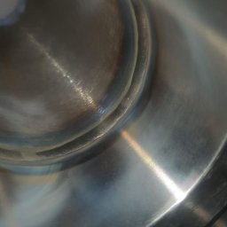 Instal-Met serwis - Szczegółowe ujęcie spoiny na metalowej konstrukcji, widoczne ślady obróbki i przebarwienia termiczne.