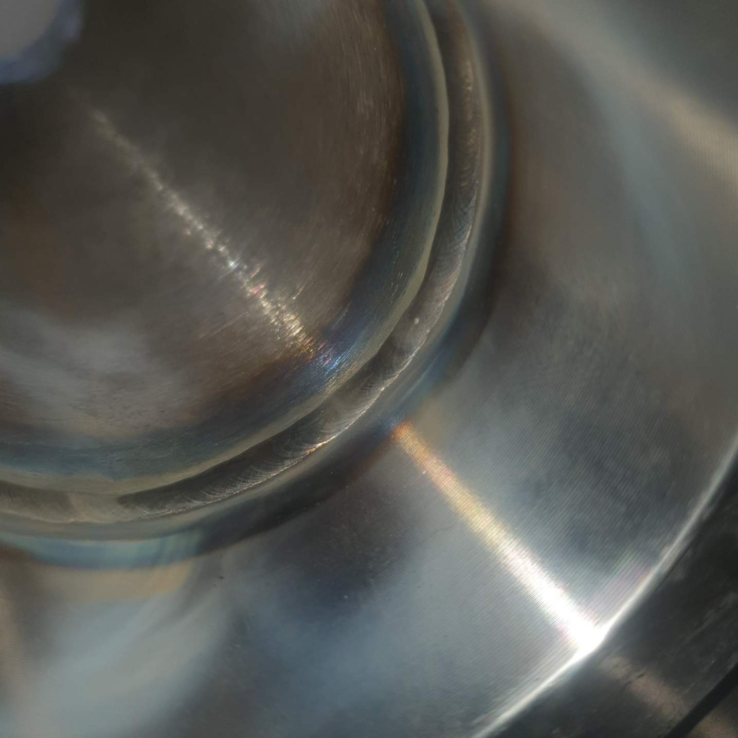 Szczegółowe ujęcie spoiny na metalowej konstrukcji, widoczne ślady obróbki i przebarwienia termiczne.