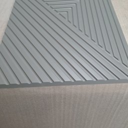 STOLARSTWO PAWEŁ KOPACZEWSKI - Szara płyta MDF z frezowanym geometrycznym wzorem koncentrycznych kwadratów, leżąca na podłożu z pianki.