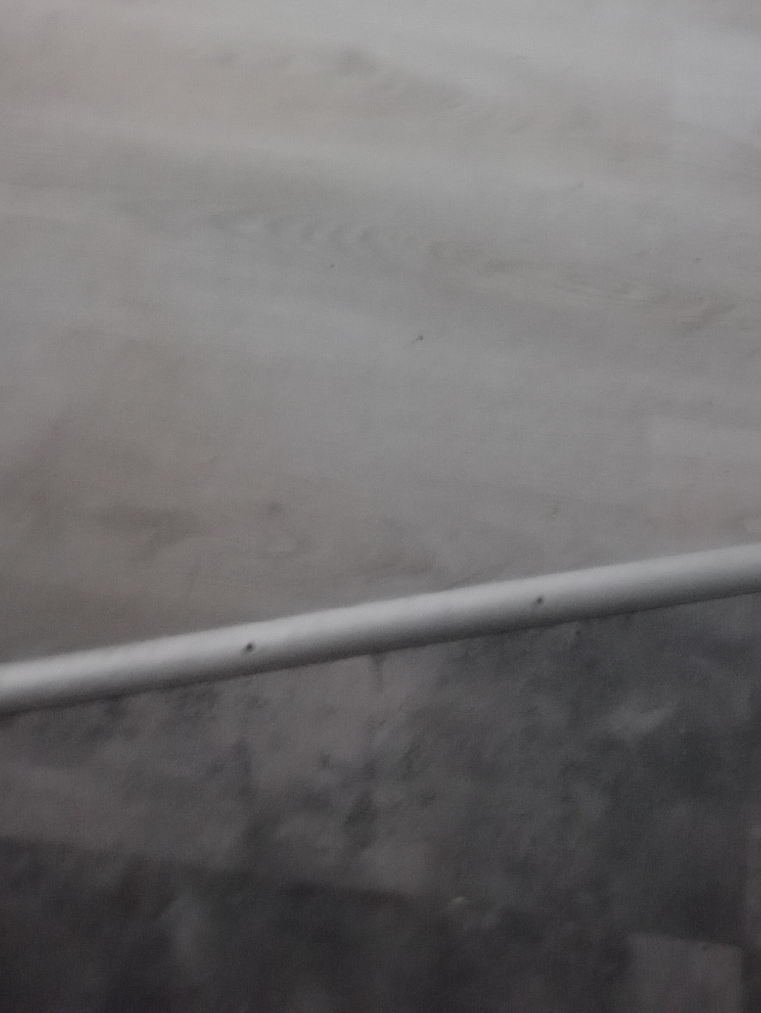 Szara, świeżo pomalowana ściana z widoczną, poziomą, metalową listwą przypodłogową.