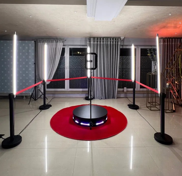 Rozstawiona fotobudka 360 z czerwonym dywanem i oświetleniem LED, odgrodzona czerwoną taśmą.
