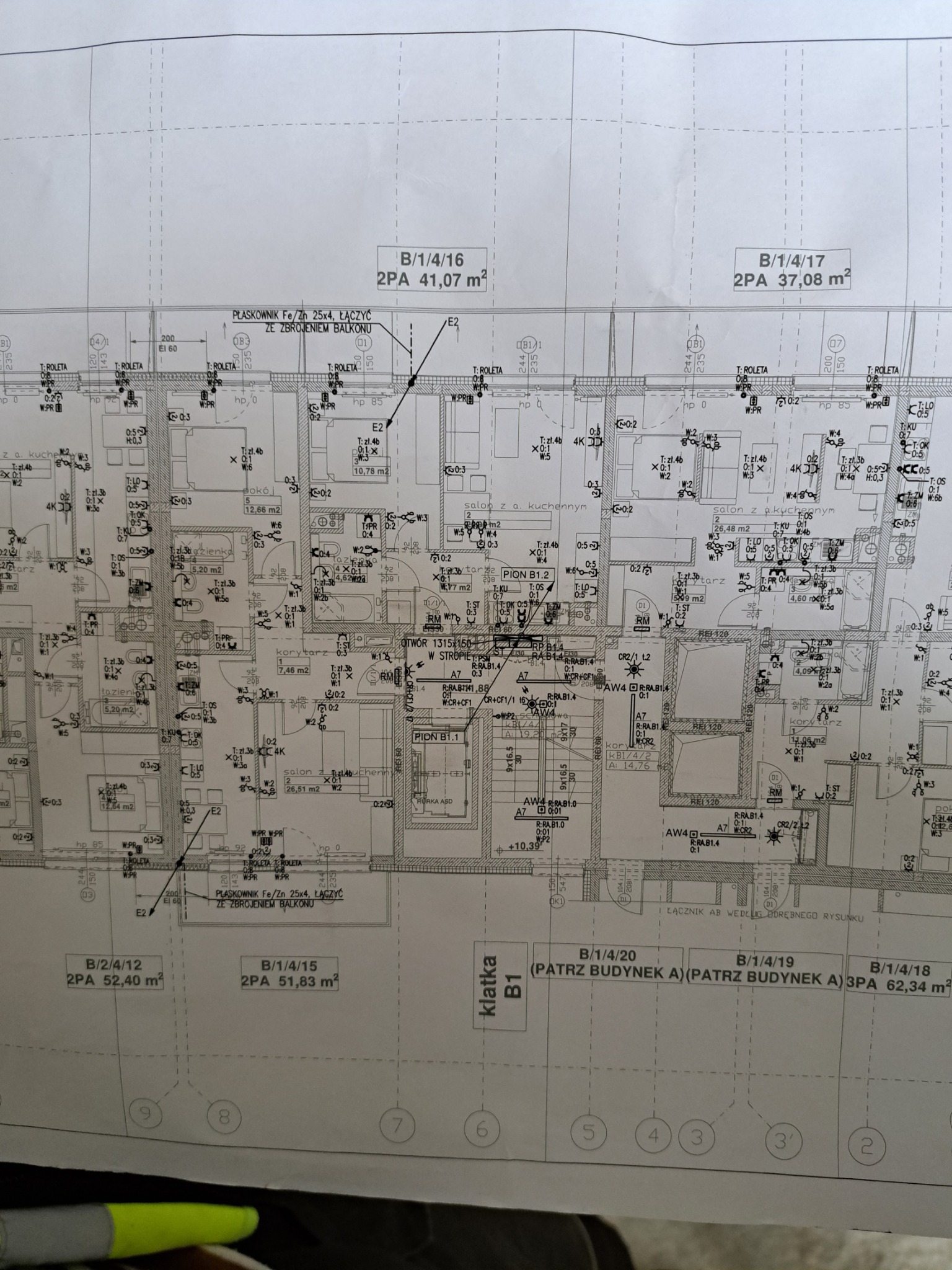 Plan elektryczny mieszkania z naniesionymi punktami oświetleniowymi, gniazdkami i trasami kabli nałożony na rzut architektoniczny, widok z góry.