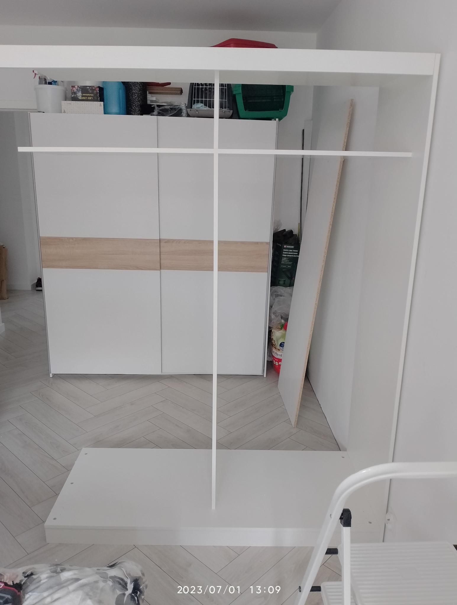 Fragment szafy z przesuwnymi drzwiami podczas montażu, widoczne elementy konstrukcyjne i drabina.