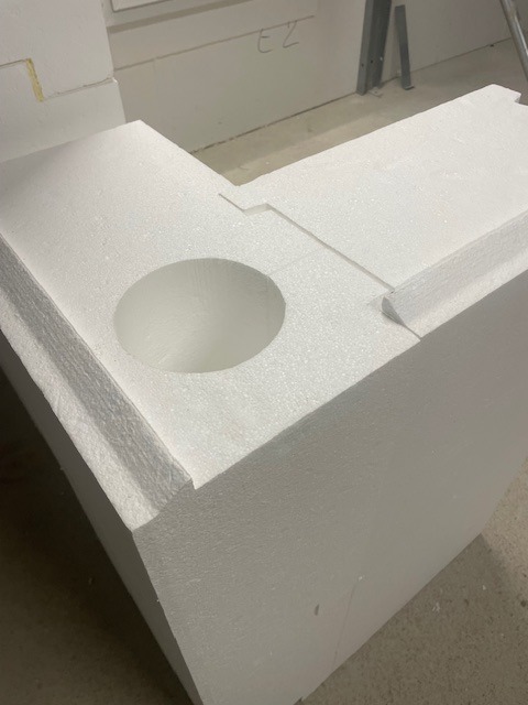 Fragment białego styropianowego szalunku traconego z okrągłym otworem, widoczny na budowie. Detal konstrukcyjny, izolacja termiczna fundamentu.