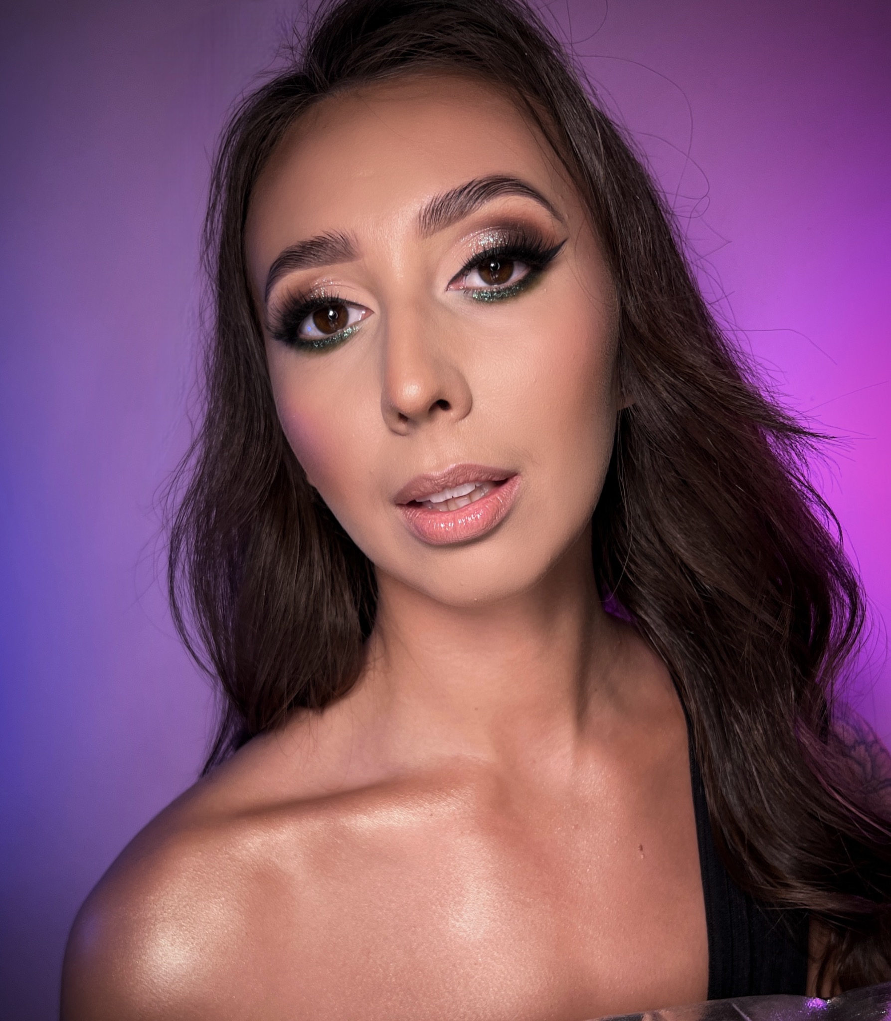 Portret kobiety z profesjonalnym, wieczorowym zdobieniem powiek w odcieniach brązu i zieleni, podkreślonymi sztucznymi rzęsami, na tle fioletowo-różowego gradientu.