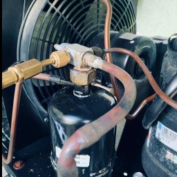 JohnnyKlima JAN GAJEWSKI - Detal klimatyzacji przemysłowej: wentylator, rury miedziane i czarny filtr. Widoczne złącza i naklejki z oznaczeniami technicznymi. Oświetlenie naturalne, kadr z bliska.