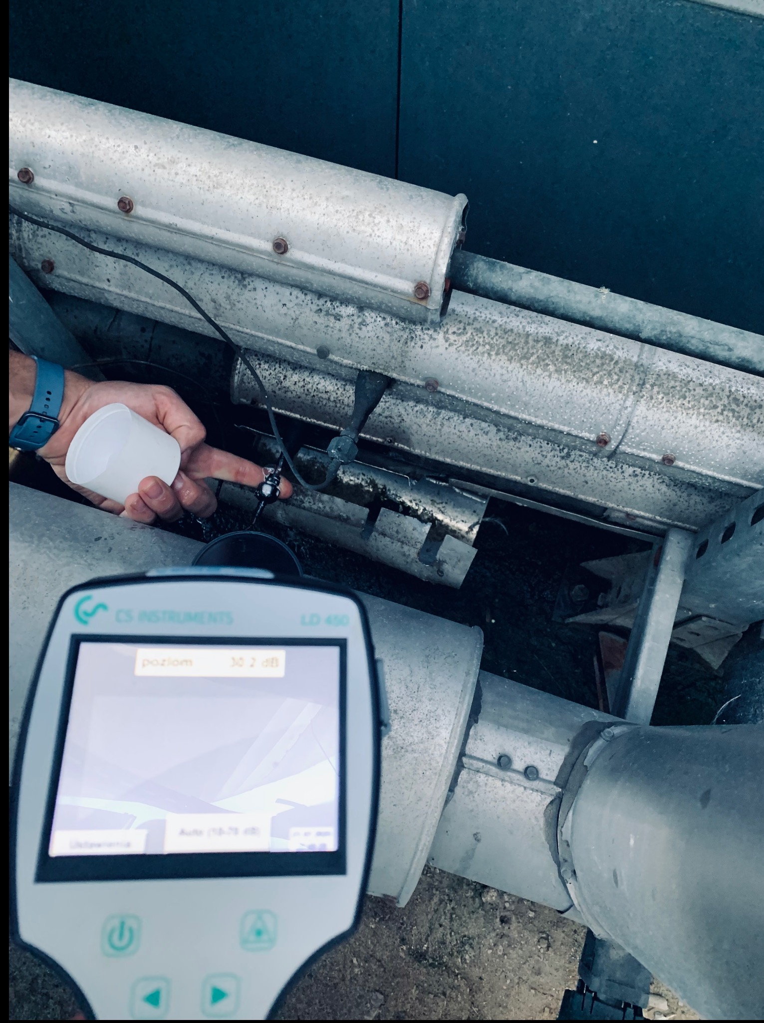 Pomiar poziomu hałasu klimatyzacji przemysłowej urządzeniem CS Instruments LD 400. Widoczna ręka trzymająca pojemnik w pobliżu czujnika.