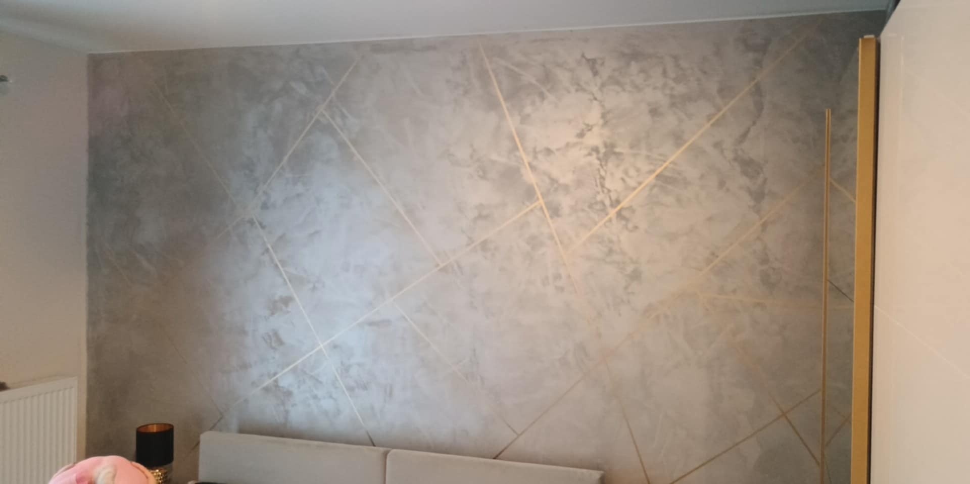 Dekoracyjna ściana w marmurkowym stylu z geometrycznymi, złotymi liniami w Stargardzie. Wykończenie wnętrz z efektem.