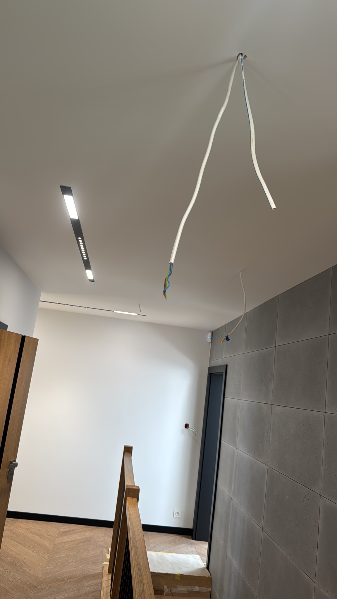Nowoczesne oświetlenie sufitowe LED i wystające przewody w Gryfinie. Widok na klatkę schodową i minimalistyczny design wnętrza.