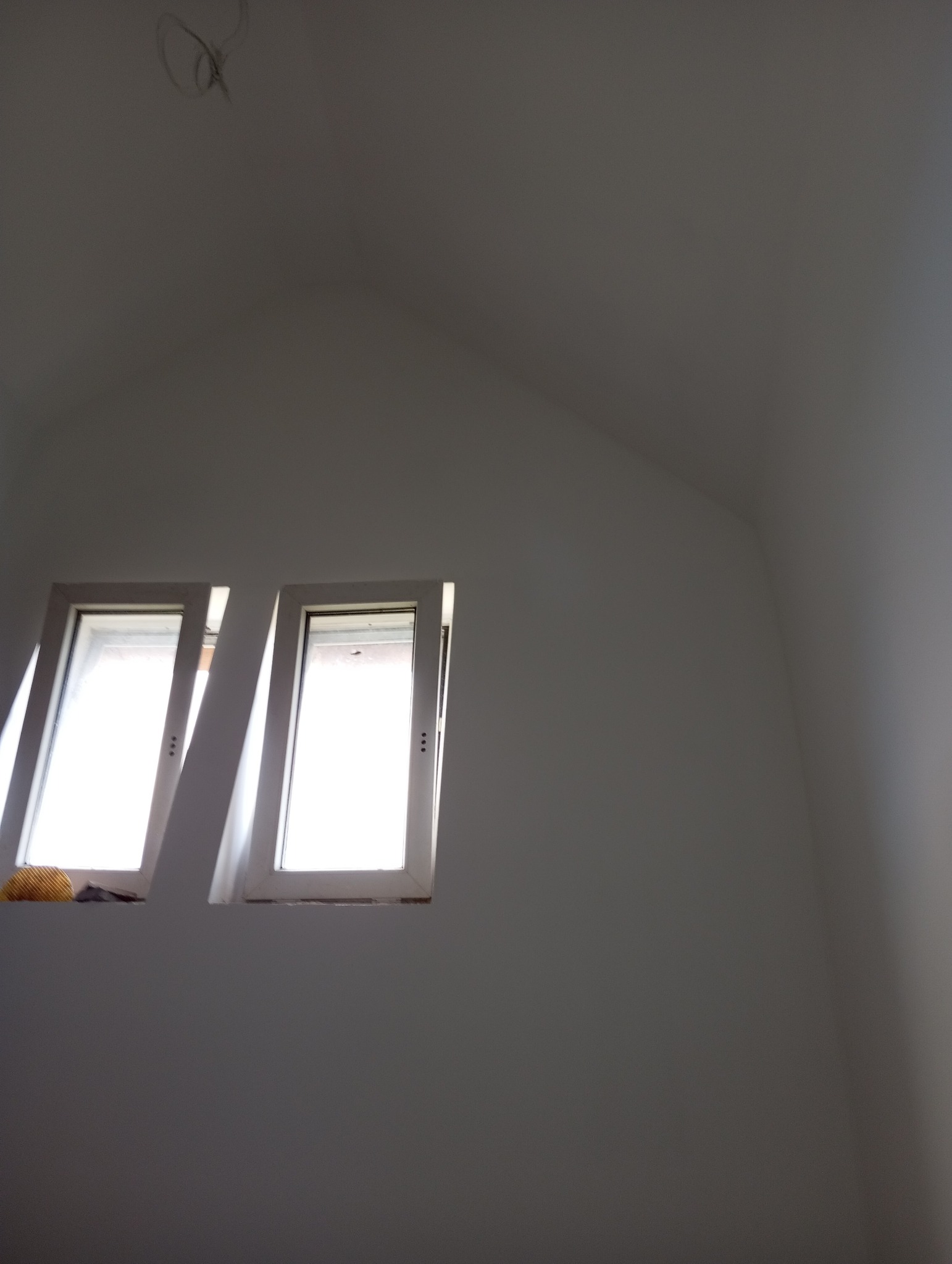 Poddasze z dwoma oknami dachowymi po malowaniu na biało, widoczne niedoskonałości na parapecie.