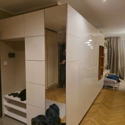 Meble w Twojej okolicy - Biała, lakierowana szafa na wymiar z lustrzanymi drzwiami przesuwnymi, tworząca garderobę i przedpokój w nowoczesnym mieszkaniu z parkietem w jodełkę.