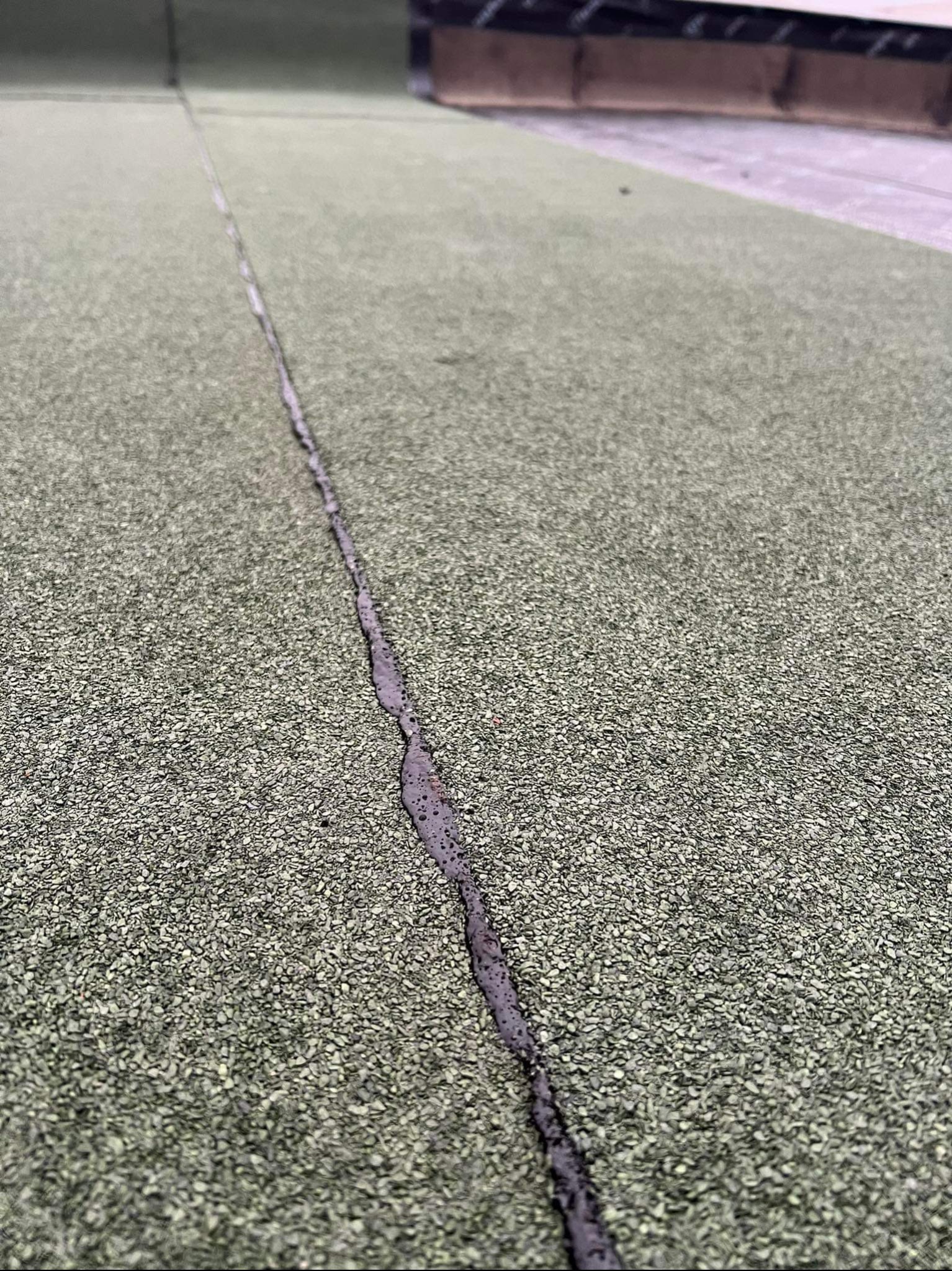 Fragment dachu pokrytego papą z widocznym, świeżo zalanym smołą łączeniem arkuszy.