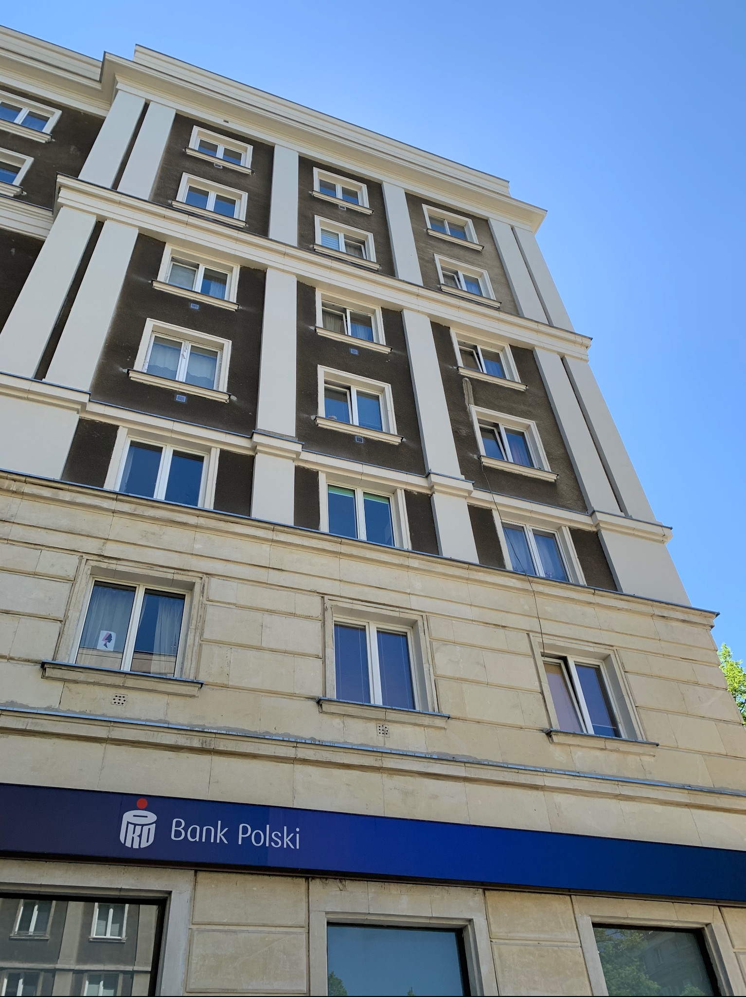 Fasada budynku Banku Polskiego z perspektywy żabiej, błękitne niebo w tle.