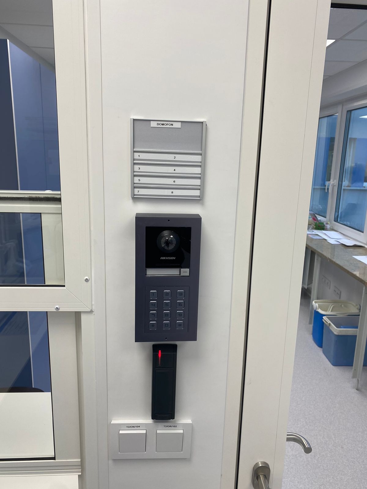 Zamontowany panel domofonowy Hikvision z czytnikiem kart zbliżeniowych i listą lokatorów przy wejściu do budynku.
