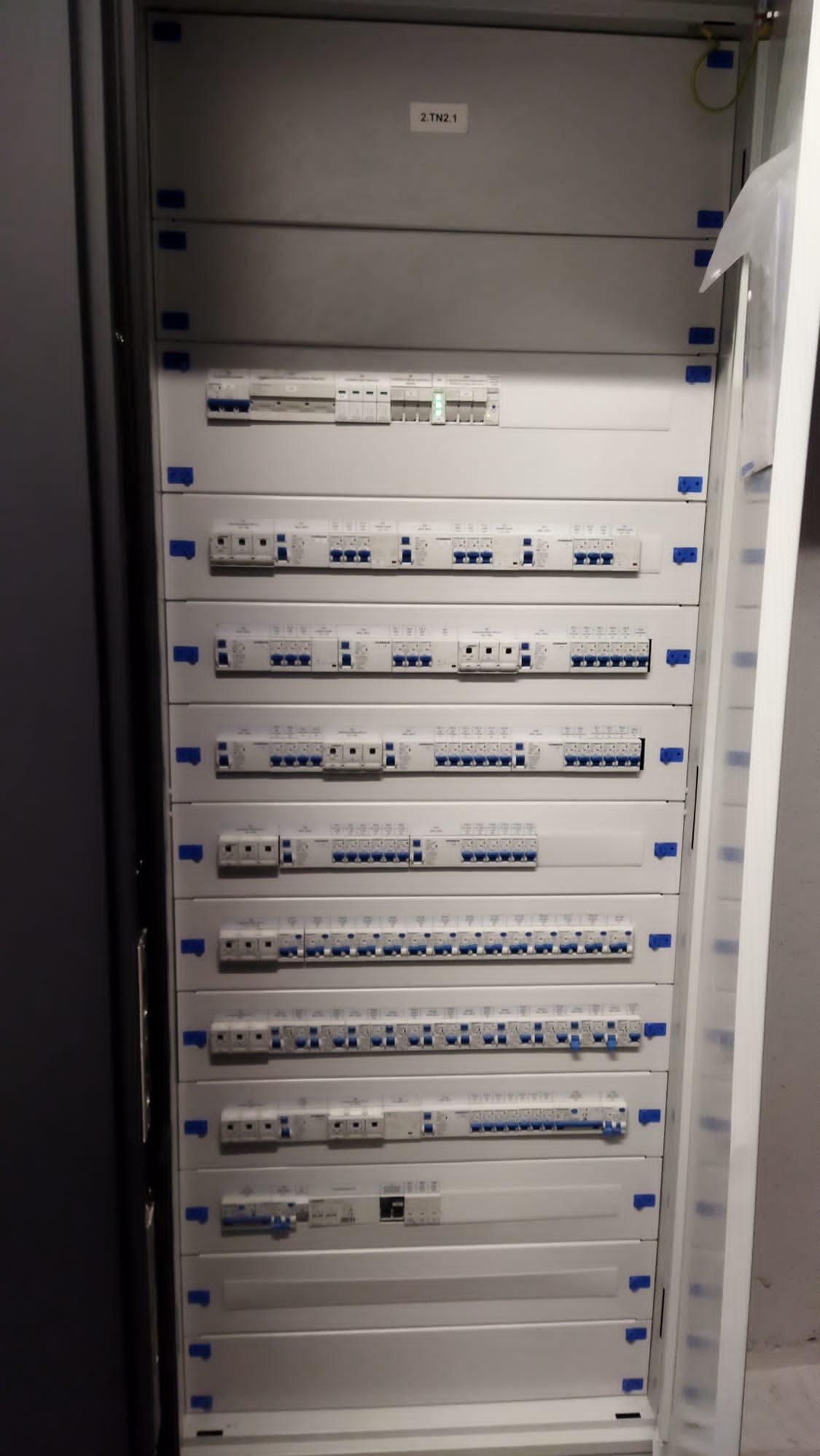 Rozdzielnica elektryczna z wieloma modułowymi wyłącznikami i zabezpieczeniami, widoczne oznaczenia 2-TN2.1 na górnej części obudowy.