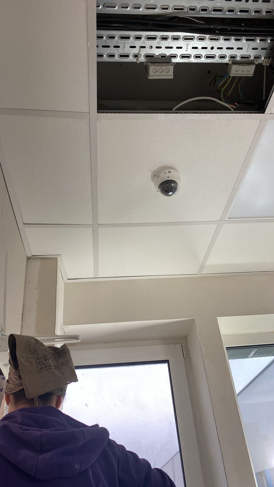 Kamera monitoringu kopułkowa zamontowana na suficie podwieszanym w biurze w Warszawie, widoczne kable i puszki instalacyjne w przestrzeni nad sufitem.