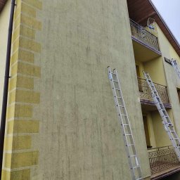 cleanup Karolina Ogrodnik - Żółta elewacja domu wielorodzinnego przed malowaniem, widoczne ślady zabrudzeń i dwie aluminiowe drabiny Krause oparte o ścianę.