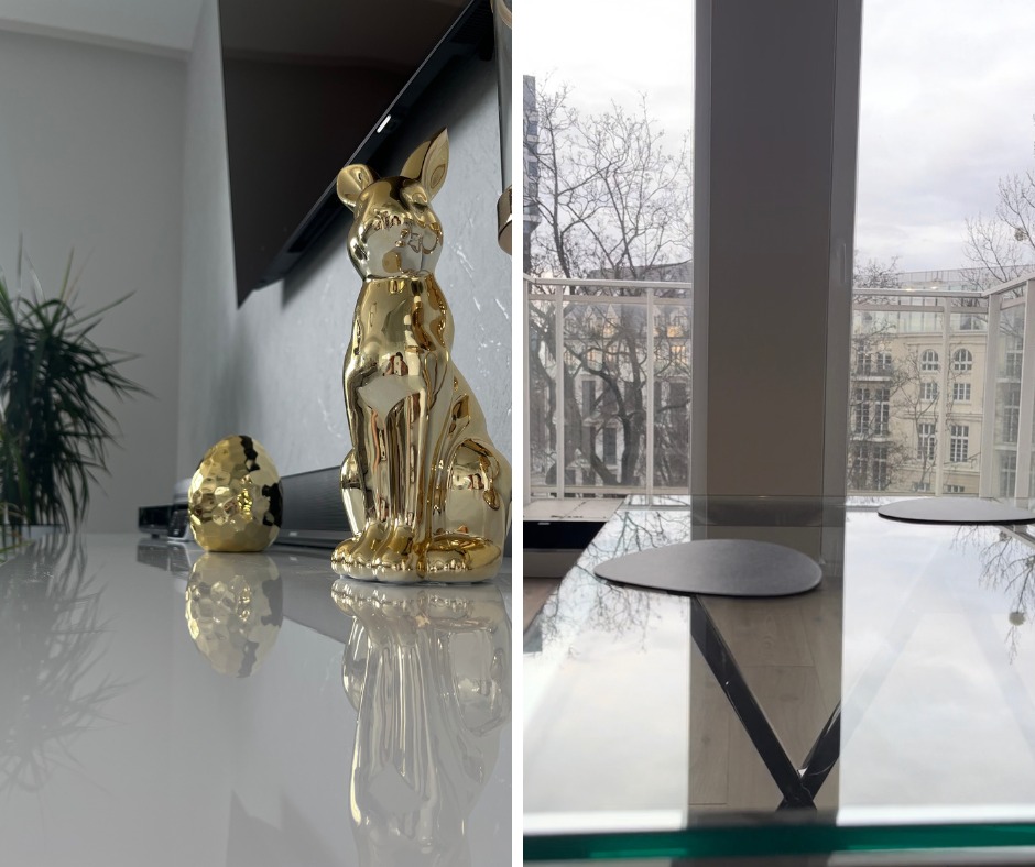 Błyszcząca, złota figurka zająca i jajka na białym, lśniącym blacie w nowoczesnym wnętrzu z dużym oknem i widokiem na budynki.