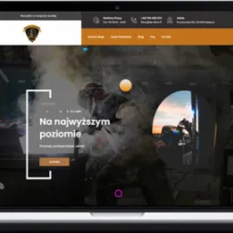 Ekran laptopa wyświetlający stronę internetową firmy z branży metalurgicznej, z logo w g&oacute;rnym lewym rogu i zdjęciem spawacza w tle, z hasłem 'Na najwyższym poziomie' oraz przyciskiem 'Kontakt'.