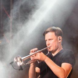 Krzysztof Raczyński - Fotografia - Muzyk grający na trąbce podczas występu na scenie w zadymionym oświetleniu punktowym.