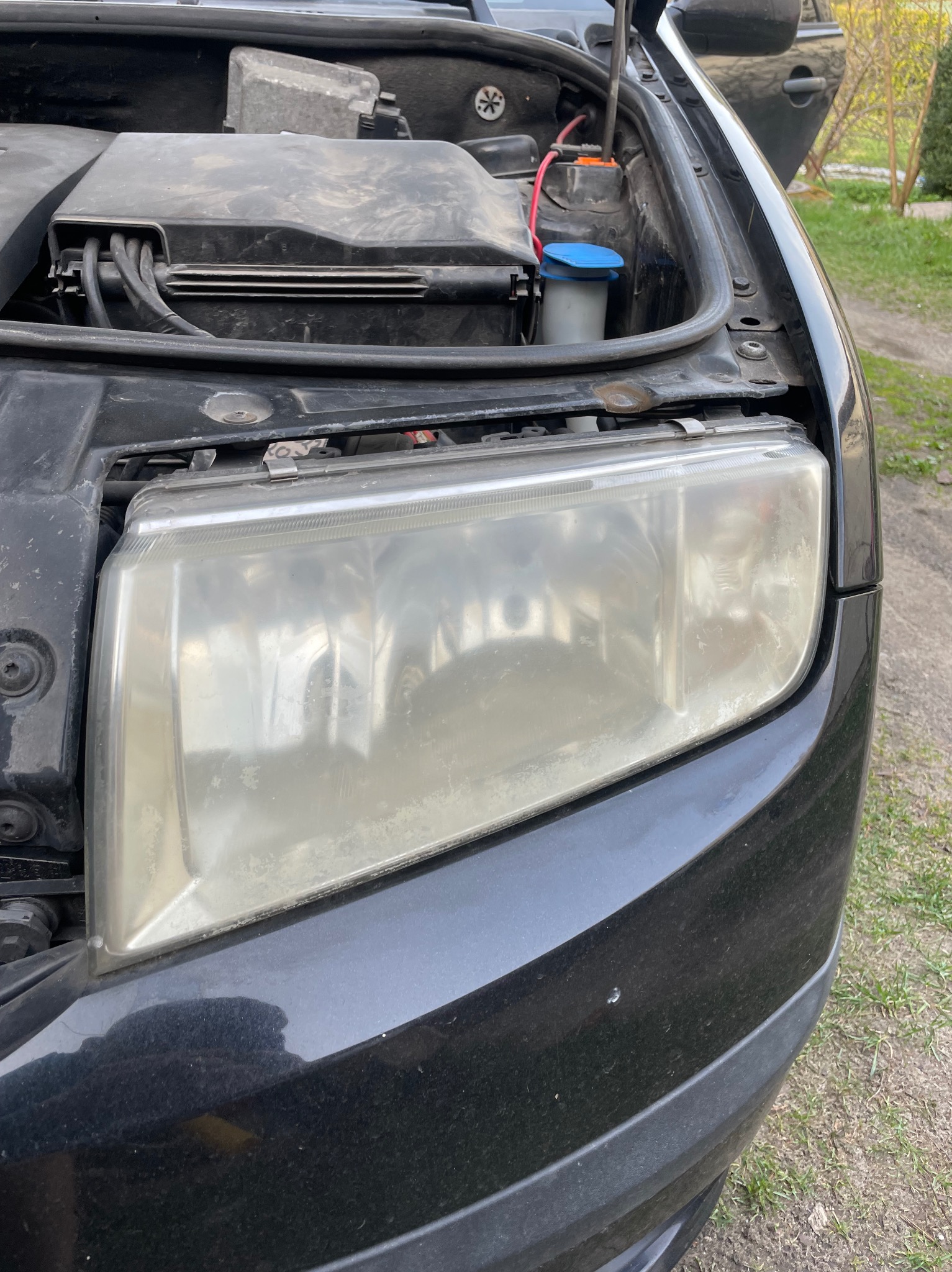 Przednia lampa samochodu z otwartą maską, widoczne zmatowienie klosza reflektora, wymagające polerowania lub wymiany.