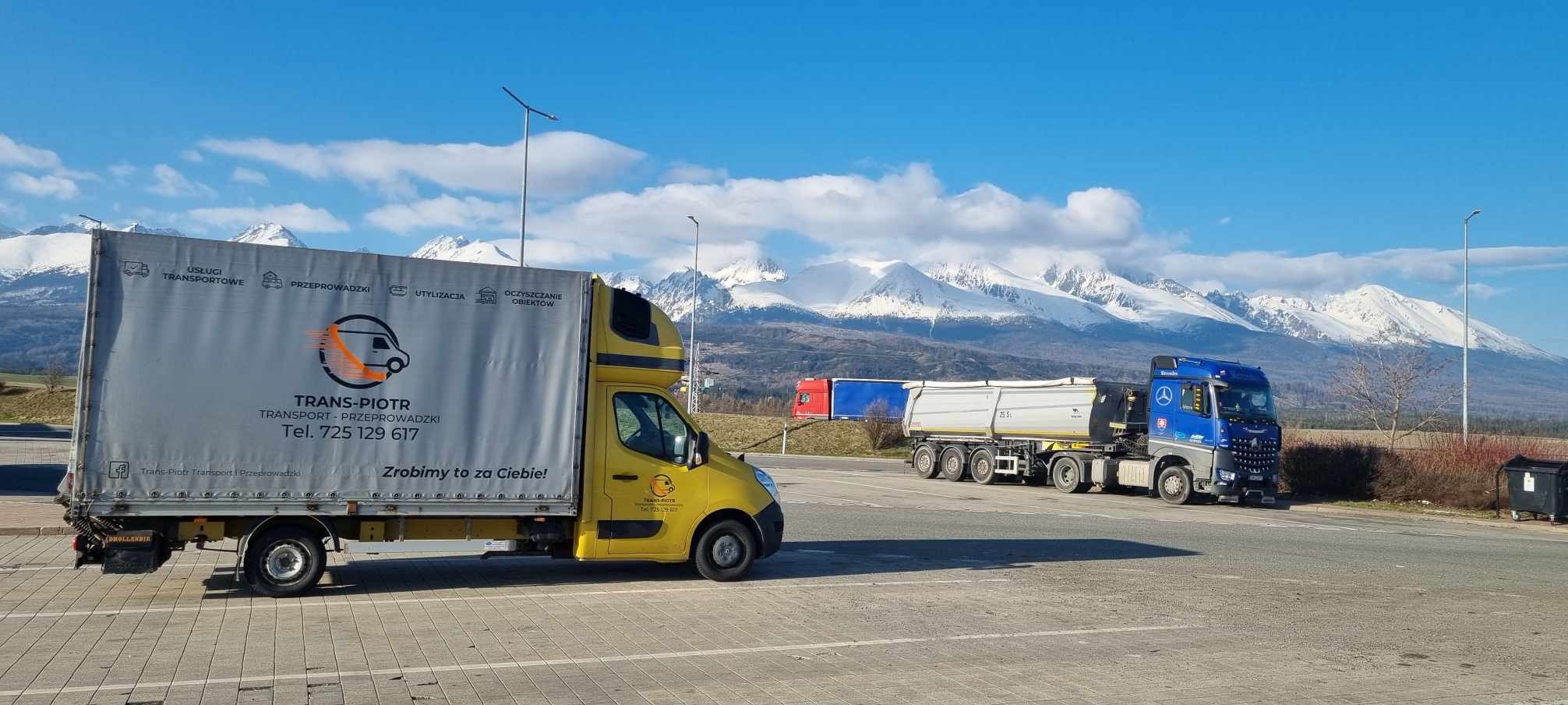 Żółty samochód dostawczy firmy Trans-Piotr z reklamą usług transportowych i przeprowadzkowych na tle górskiego krajobrazu ze śnieżnymi szczytami.