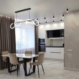 Maxxxbud - Nowoczesna jadalnia z marmurową podłogą, designerską lampą i minimalistyczną zabudową kuchenną w bieli i czerni. Stonowana kolorystyka i eleganckie wykończenie.