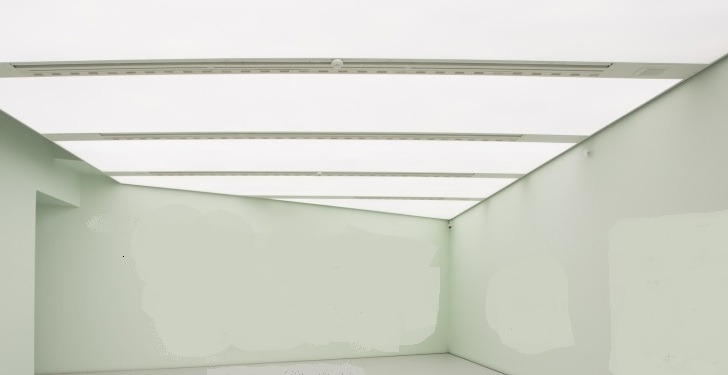 Sufit napinany z oświetleniem LED w galerii, widoczne białe panele sufitowe z liniami świetlnymi, jasne ściany w tle.