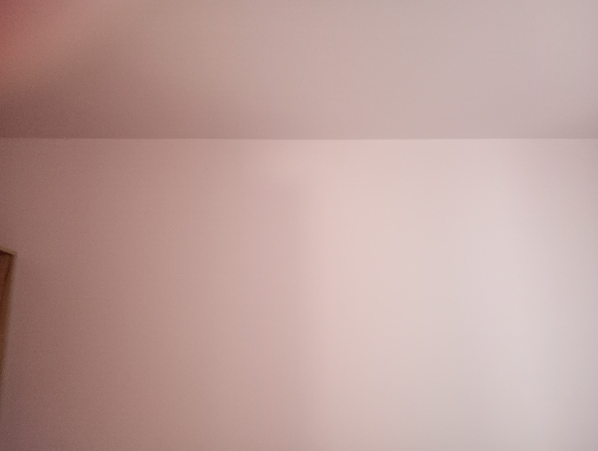 Różowa ściana po malowaniu, widoczny fragment futryny drzwi po lewej stronie.