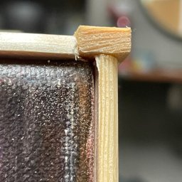 Aleksander Musioł - Detail of a wooden frame corner joint, showing a dowel and mitered edge, with visible glue residue.