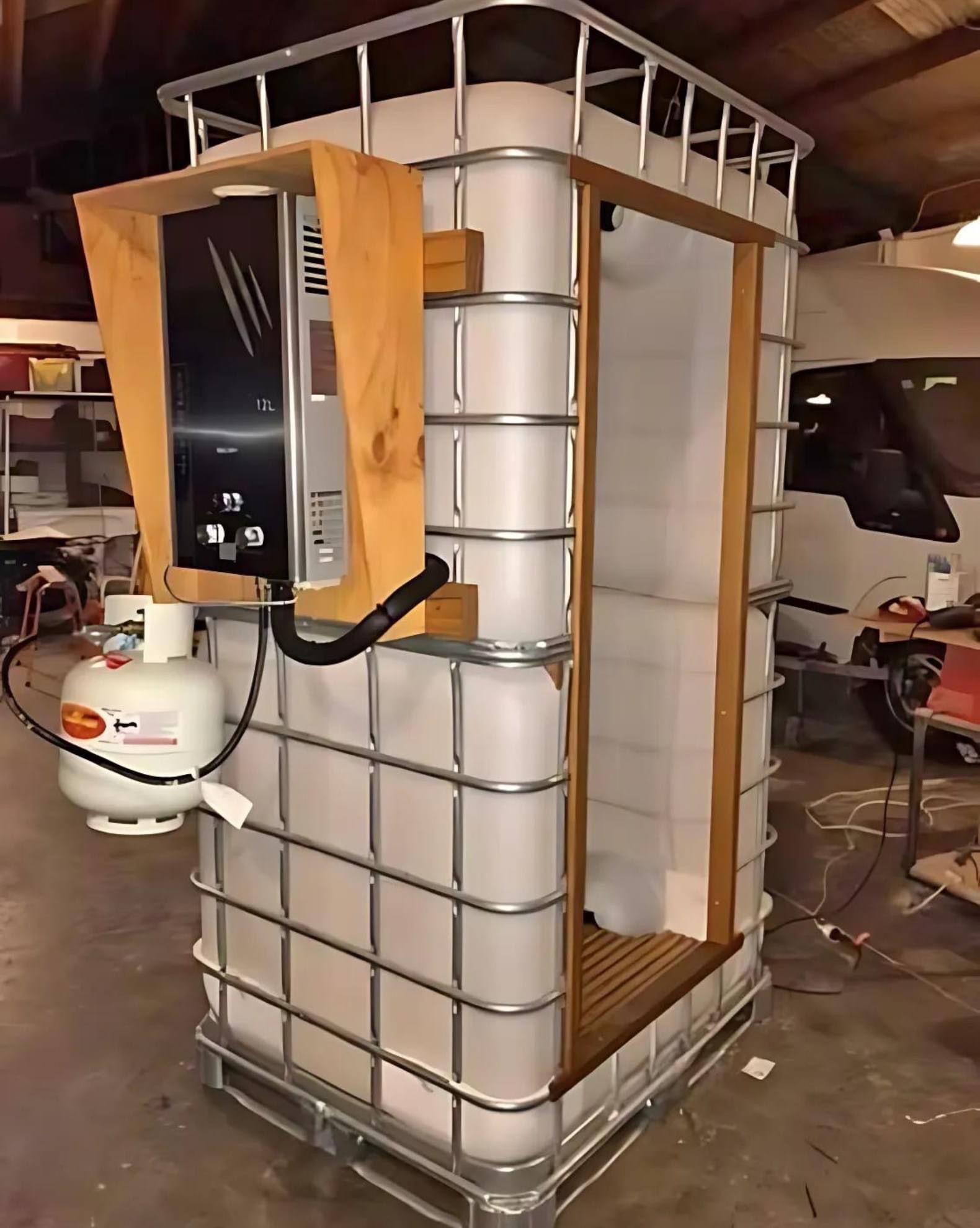 Samodzielnie wykonana kabina prysznicowa z podgrzewaczem gazowym, umieszczona w zbiorniku IBC z metalowym stelażem i drewnianą obudową.