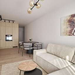 Wito - Remonty - Jasne wnętrze mieszkania z aneksem kuchennym, okrągłym stołem z krzesłami i beżową sofą, oświetlone lampą sufitową z kulistymi kloszami i ozdobione obrazem na ścianie.