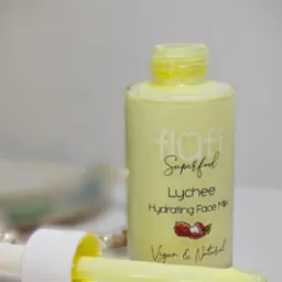 Butelka z mleczkiem do twarzy o zapachu liczi z pipetą, na rozmytym tle widać perły.