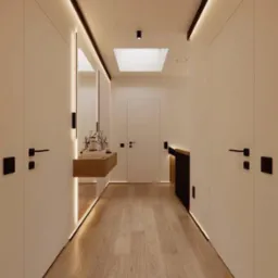 Nowoczesny korytarz z białymi ścianami, drewnianą podłogą, oświetleniem LED wzdłuż sufitu i podłogi, oraz minimalistyczną konsolą z dekoracjami.