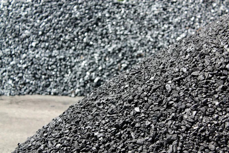 Dwa duże pryzmy węgla: ciemny, błyszczący węgiel na pierwszym planie i szary, matowy węgiel w tle.