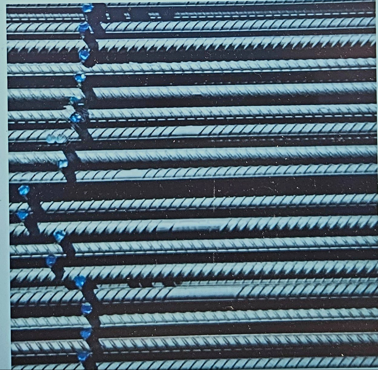 Rzędy prętów zbrojeniowych ułożone równolegle, z widocznymi niebieskimi elementami mocującymi.