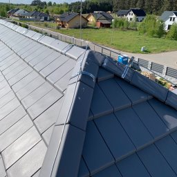 IWOPOWER Ivan Popynchuk - Szary dach z zamontowaną instalacją odgromową, widok z góry na tle zabudowy jednorodzinnej i lasu.