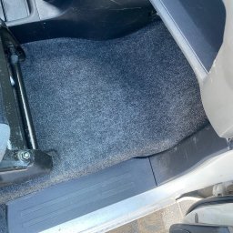 BÓBR CLEANING OLHA BEBRISA - Szara wykładzina podłogowa w samochodzie, widoczny fragment fotela i progu.