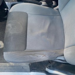 BÓBR CLEANING OLHA BEBRISA - Szare, zabrudzone siedzenie samochodowe z widocznymi plamami i niewielkim uszkodzeniem tapicerki, sfotografowane z góry.