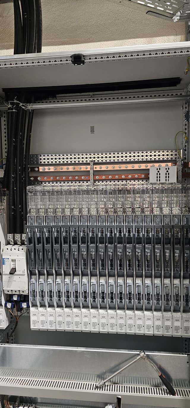 Rozdzielnia elektryczna z zabezpieczeniami i miedzianymi szynami w Strzebiniu, widoczny klucz nasadowy.