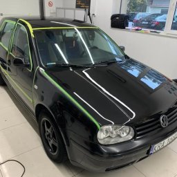 Bomba Garage Auto Detailing - Czarny samochód Volkswagen Golf IV przygotowywany do oklejania, z zieloną taśmą maskującą wokół szyb i elementów karoserii, widoczne tablice rejestracyjne KRA 16668.
