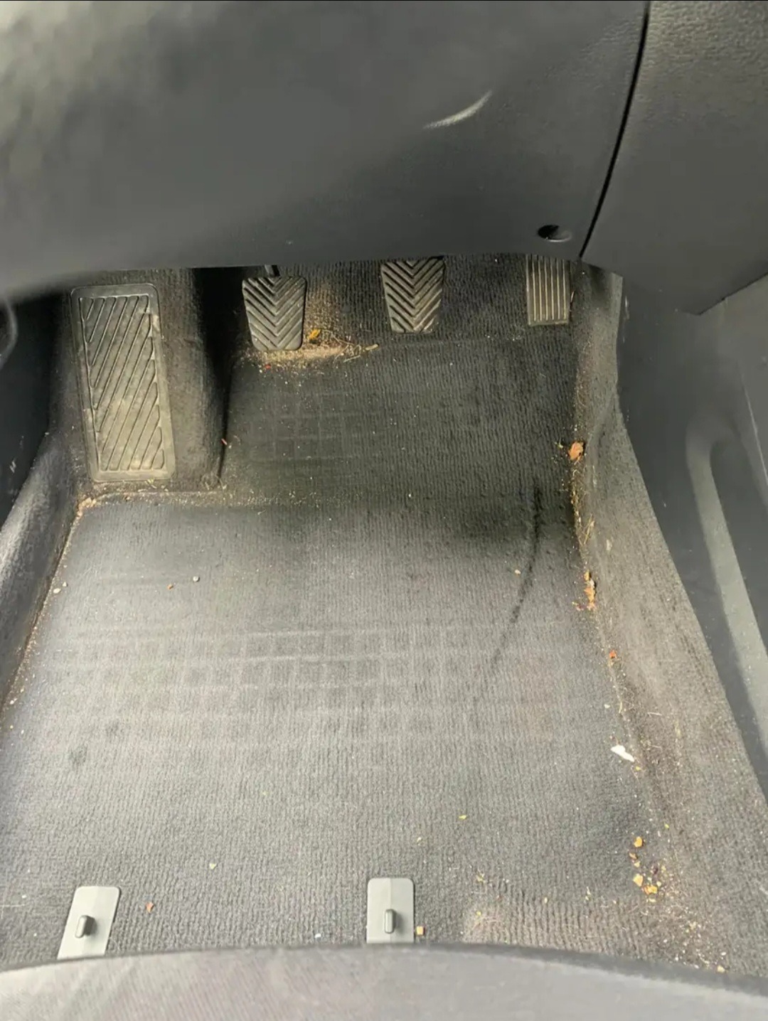 Wnętrze samochodu przed czyszczeniem: brudna podłoga i pedały z widocznymi zanieczyszczeniami.