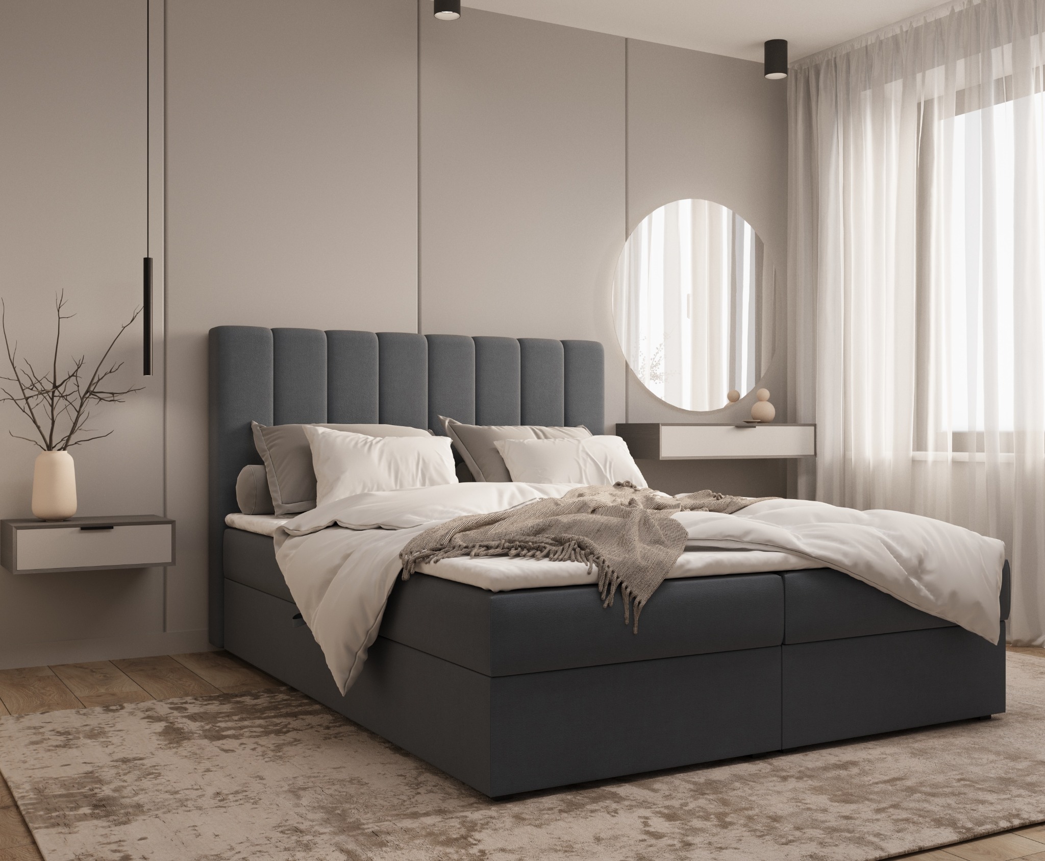 Nowoczesna sypialnia z szarym łóżkiem kontynentalnym, białymi poduszkami i narzutą, okrągłym lustrem oraz minimalistyczną szafką nocną z dekoracją z gałązek.