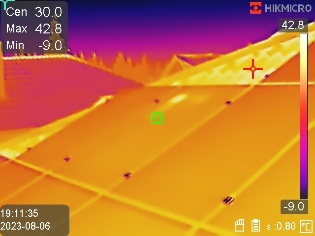 Termowizja dachu z zaznaczonymi punktami pomiarowymi, widoczne różnice temperatur w odcieniach żółci, pomarańczy i fioletu, z naniesionymi danymi pomiarowymi.